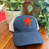 Navy blue cap with red logo and text on a wooden surface with plants in the background